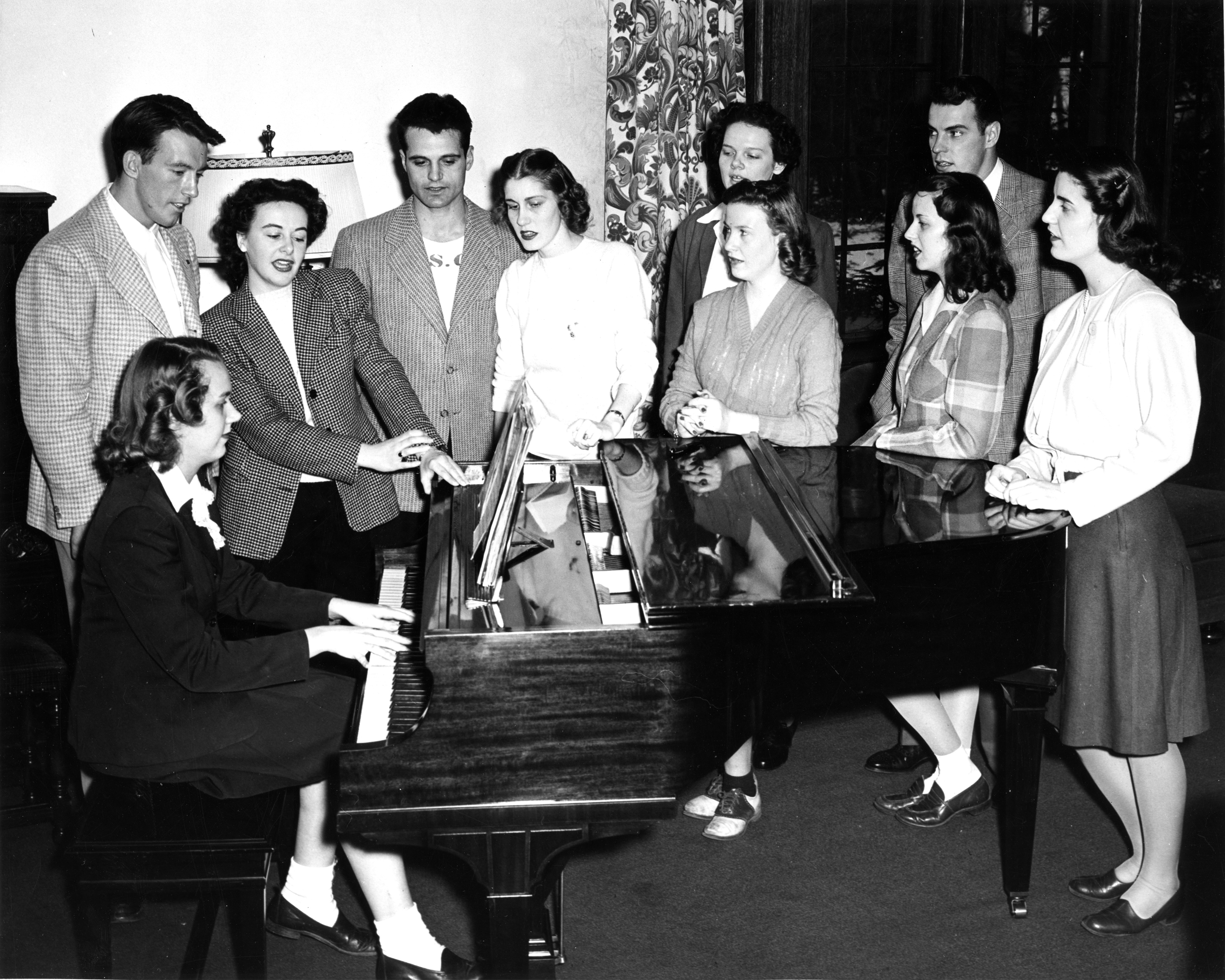 Students gather around a piano, circa 1950