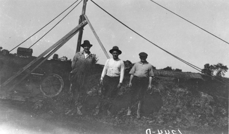 Three men pose near drag line, unknown date