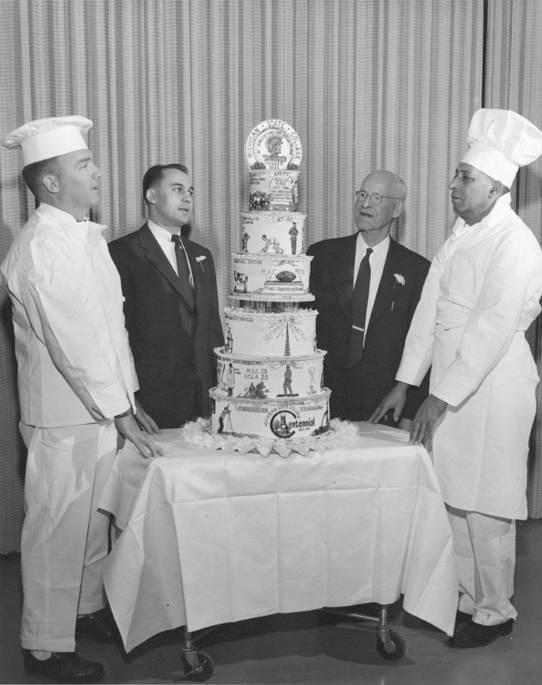 Bakers alongside MSU centennial cake, 1955