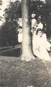 Six students pose behind a tree, date unknown
