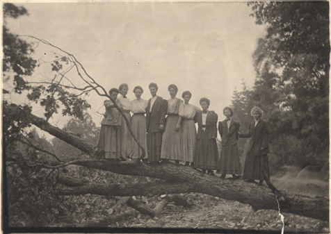 Students standing on a tree, ca. 1910 