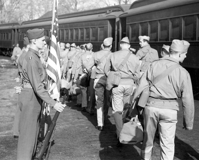 Military students walk next to a train, ca. 1940