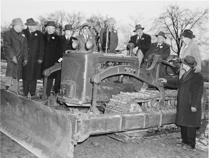 Men surround a tractor to begin construction, ca. 1949 