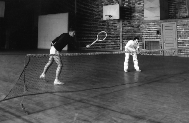 Two men play tennis in a gymnasium, 1936