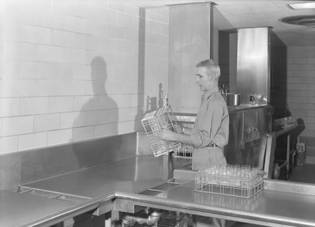 Employee using dishwasher in dorm kitchen, 1955