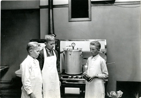 Three young boys canning food in a kitchen