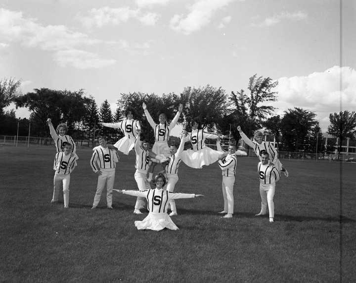 Cheerleading team posing on field, 1964
