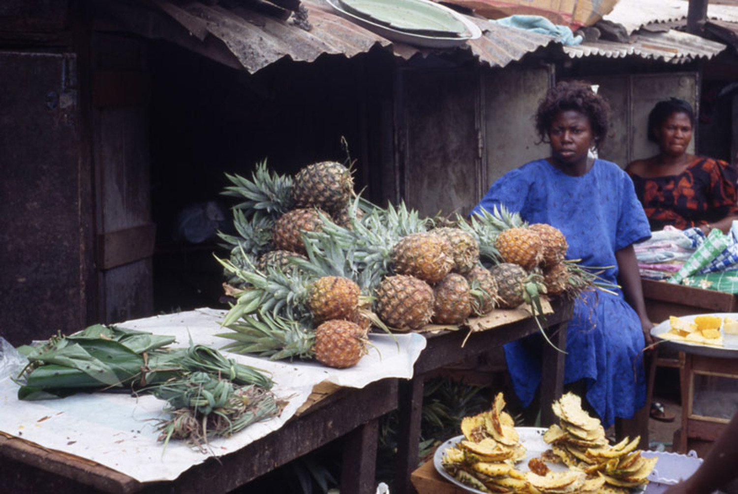 Youngish woman seated with pineapples. she sells plantain in season