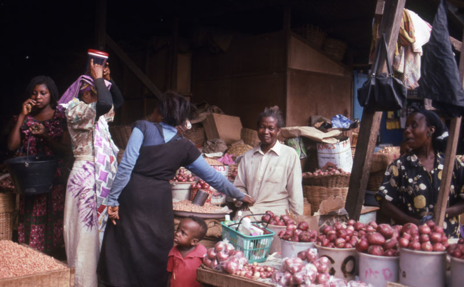 Onion trader at corner of onion shed with customers